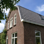 Voor en zij aanzicht van een jaren 20 huis met baksteen en overstekend schuin dak.